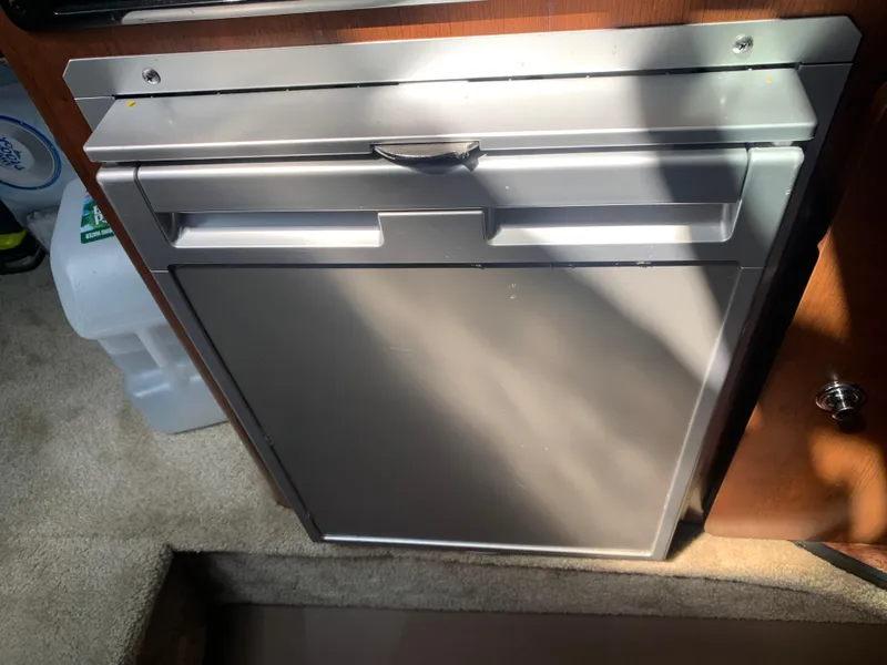 Slide: The Image of Compact refrigerator inside 2018 Crownline 264 CR boat cabin, with sunlight casting shadows. - 27