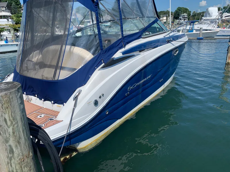 Slide: The Image of 2018 Crownline 264 CR boat docked in marina, featuring blue and white exterior. - 3