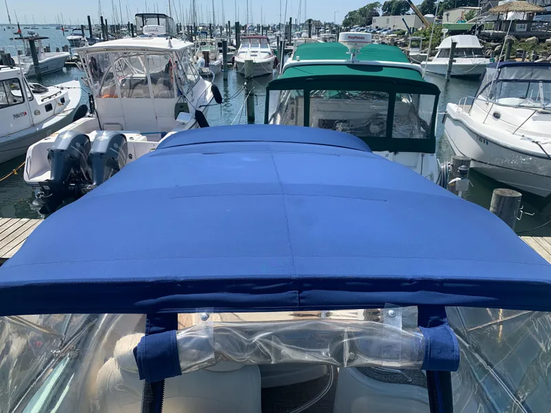 Slide: The Image of 2018 Crownline 264 CR boat with blue canopy docked among other boats. - 39