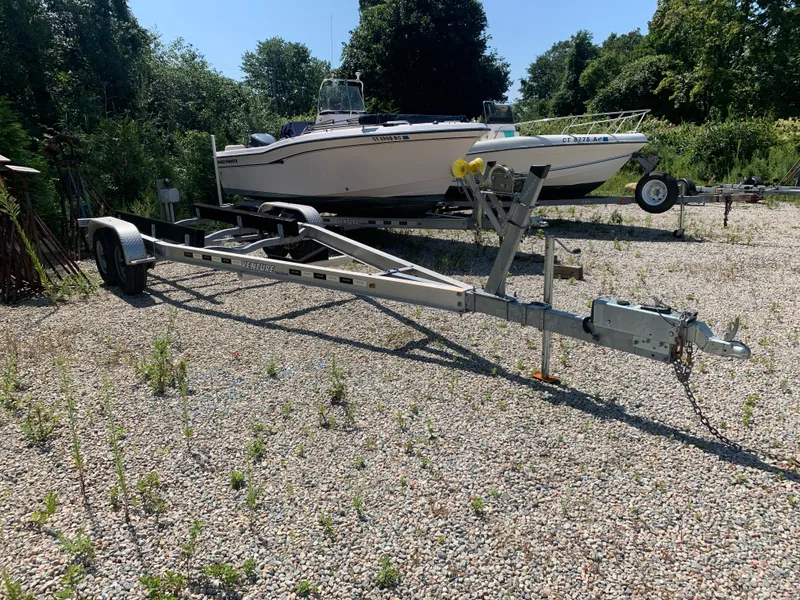 Slide: The Image of Trailer for 2018 Crownline 264 CR boat on gravel lot with greenery. - 46