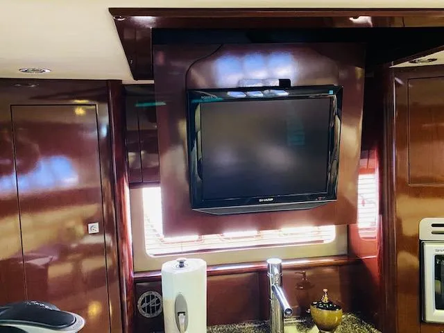 Slide: The Image of Interior of 2008 Sea Ray 440 Sundancer with mounted TV and wooden cabinetry. - 17