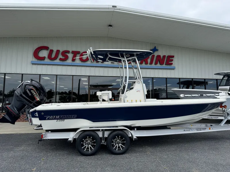 The Image of 2025 Pathfinder 2300 HPS boat on trailer outside Custom Marine dealership. - 1