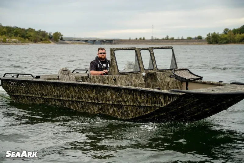 The Image of 2025 SeaArk Predator boat on trailer, parked outside industrial building. - 1