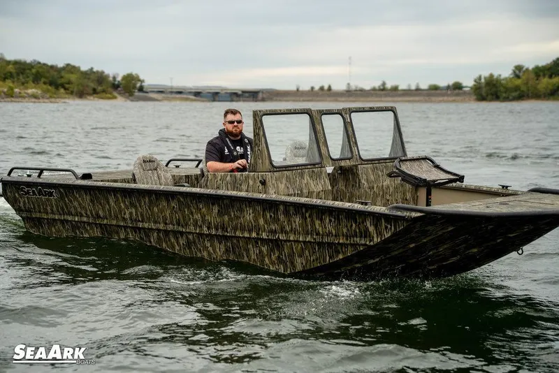 Slide: The Image of 2025 SeaArk Predator boat speeding on a lake with scenic background. - 28