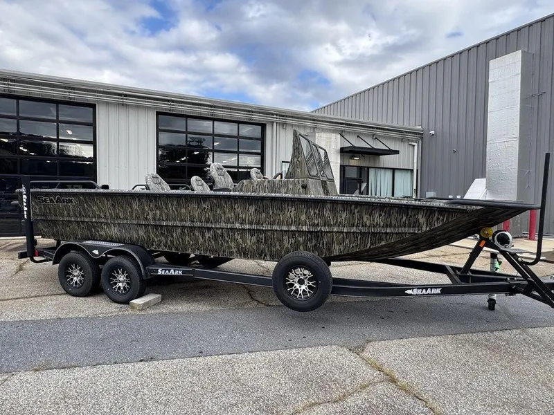 Slide: The Image of 2025 SeaArk Predator boat on trailer, parked outdoors near industrial building. - 7