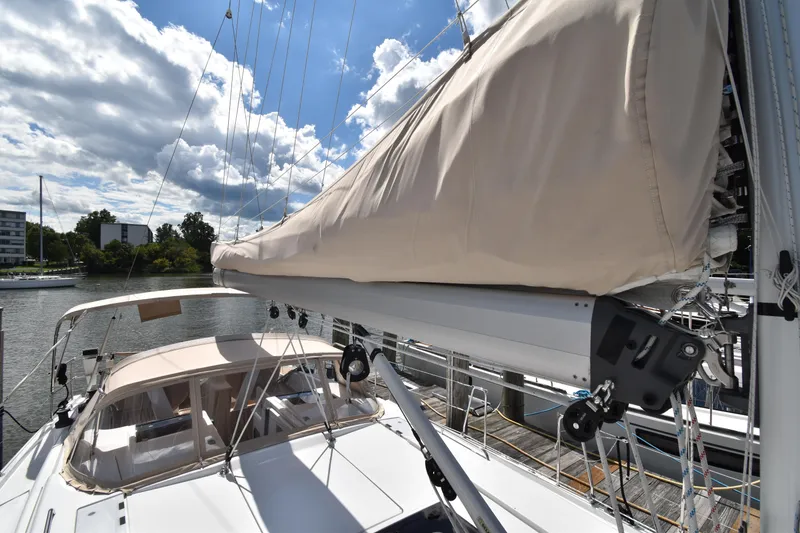 Slide: The Image of 2019 Hanse 458 sailboat with beige sail cover, docked under a partly cloudy sky. - 12