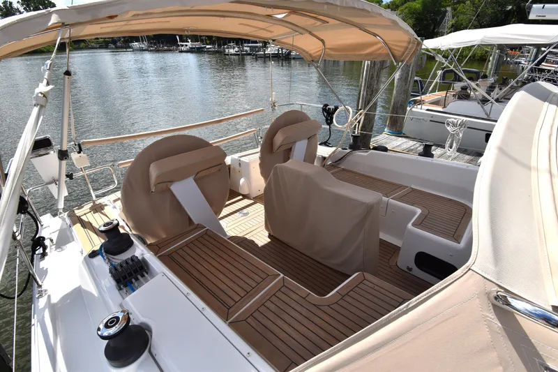 Slide: The Image of 2019 Hanse 458 yacht with teak deck and beige canopy docked by the water. - 14