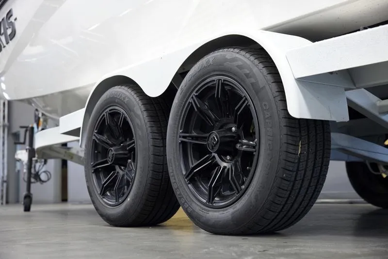 Slide: The Image of 2025 Axis A225 trailer with black wheels and white fenders in a garage. - 6