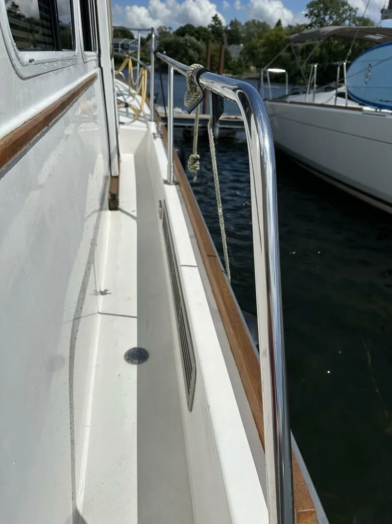 Slide: The Image of 2003 Sabre 36 Fly Bridge Sedan yacht deck with railing, docked by water. - 10
