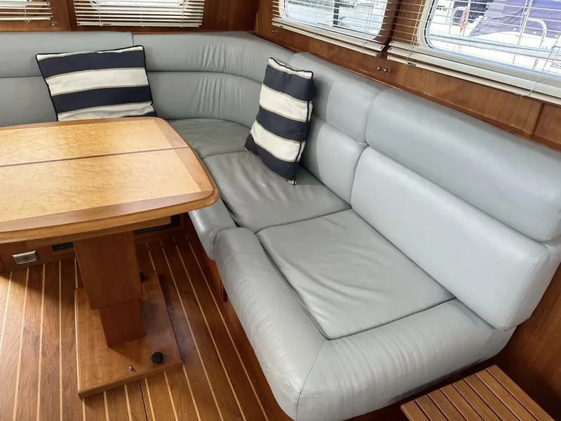 Slide: The Image of 2003 Sabre 36 Fly Bridge Sedan interior with gray leather seating and wooden table. - 25