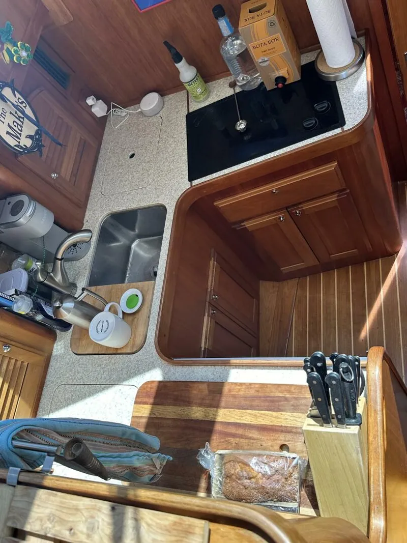 Slide: The Image of 2003 Sabre 36 Fly Bridge Sedan kitchen with sink, stove, and wooden cabinetry. - 31