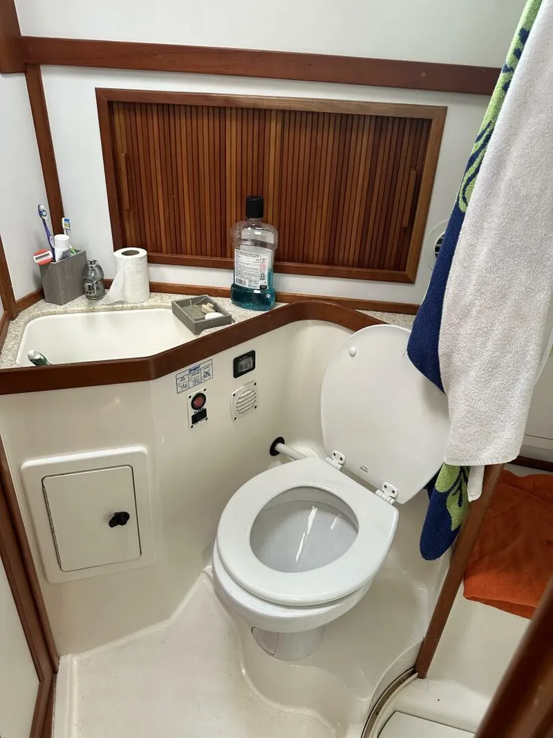 Slide: The Image of 2003 Sabre 36 Fly Bridge Sedan bathroom with toilet, sink, and wooden accents. - 48