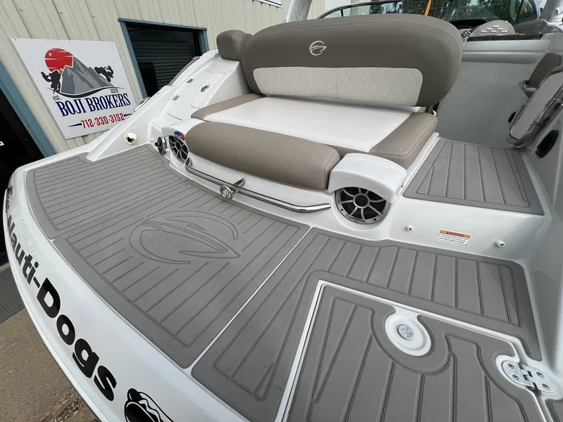 Slide: The Image of 2019 Crownline Eclipse E285 boat with cushioned seating and branded flooring at a dealership. - 8