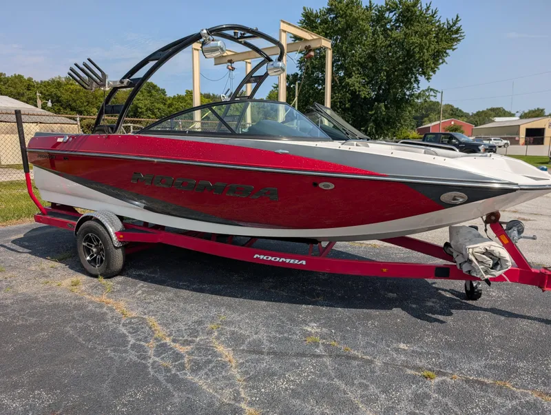 Slide: The Image of 2014 Moomba Mondo boat in red and white on a trailer, parked outdoors. - 10