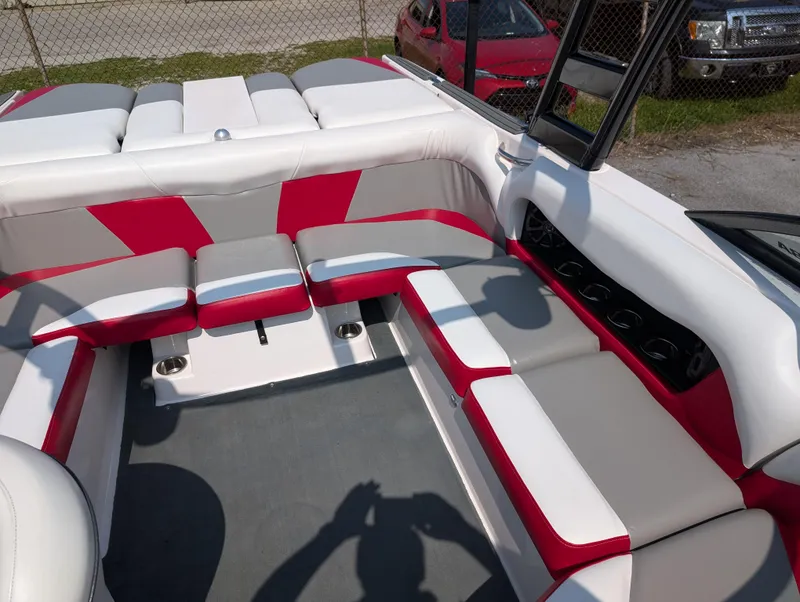 Slide: The Image of 2014 Moomba Mondo boat interior with red and white seating, gray flooring, and cup holders. - 17