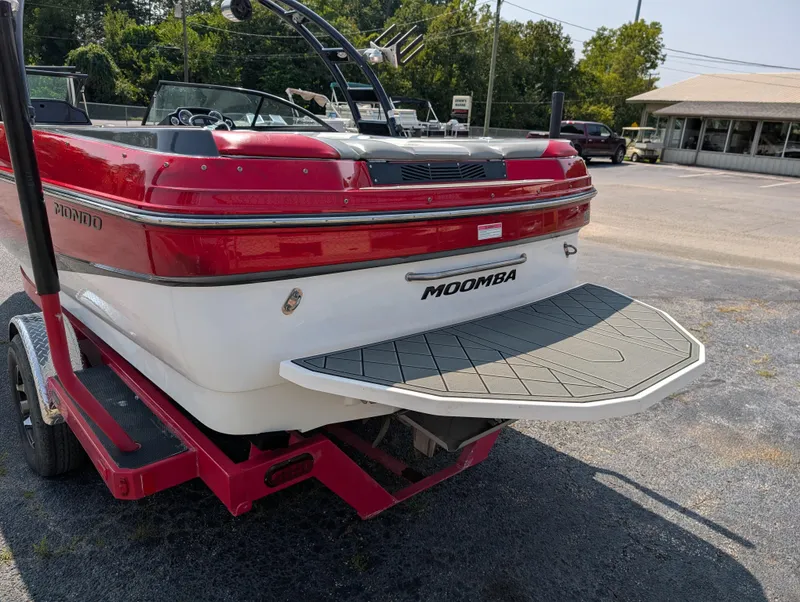 Slide: The Image of 2014 Moomba Mondo boat with red and white exterior, parked on a trailer. - 8