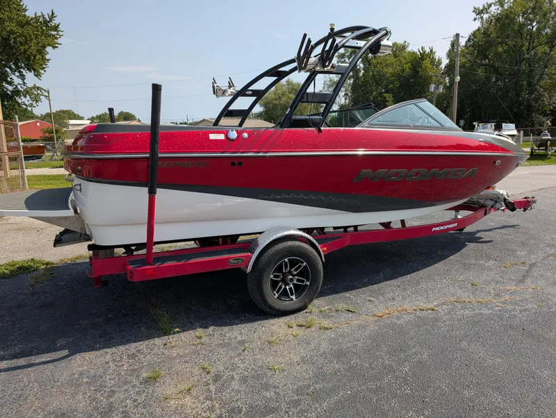 Slide: The Image of 2014 Moomba Mondo boat on trailer, red and white design, parked outdoors. - 9