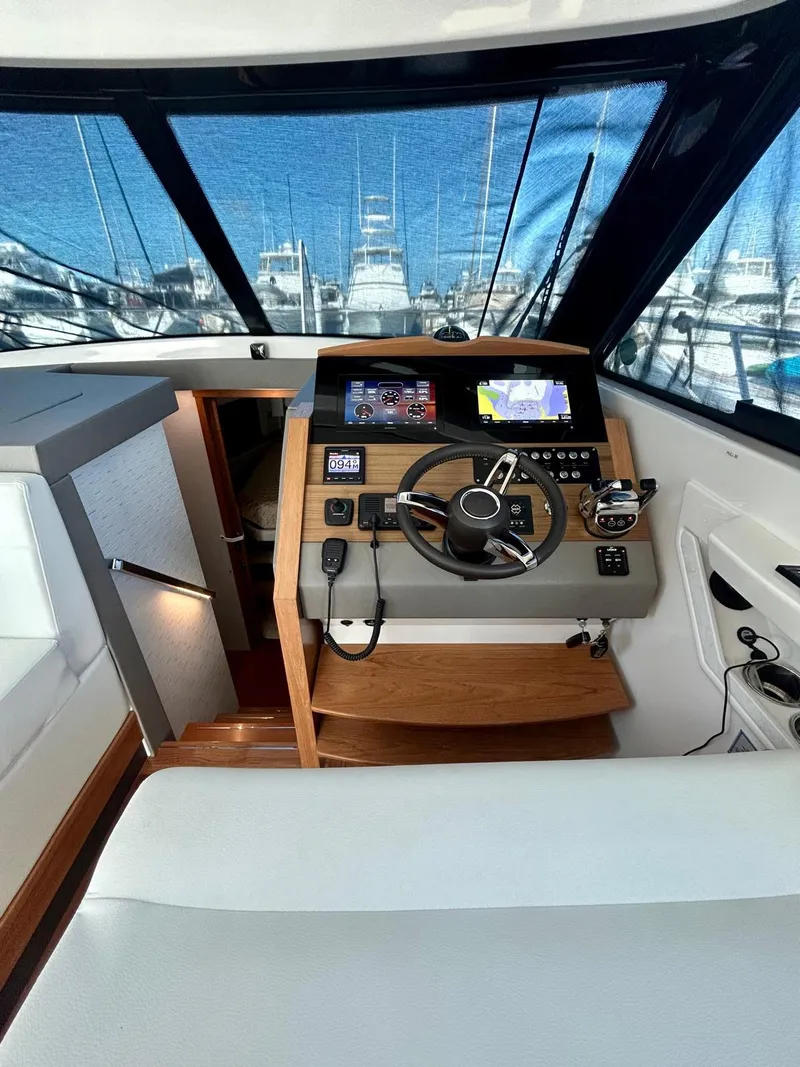 Slide: The Image of 2022 Tiara Yachts C39 Coupe helm with modern navigation controls and panoramic marina view. - 7