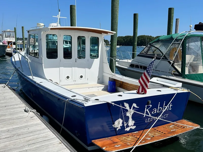 Slide: The Image of Mast & Mallet Rabbit 34 boat, 1998 model, docked with American flag, blue and white design. - 0