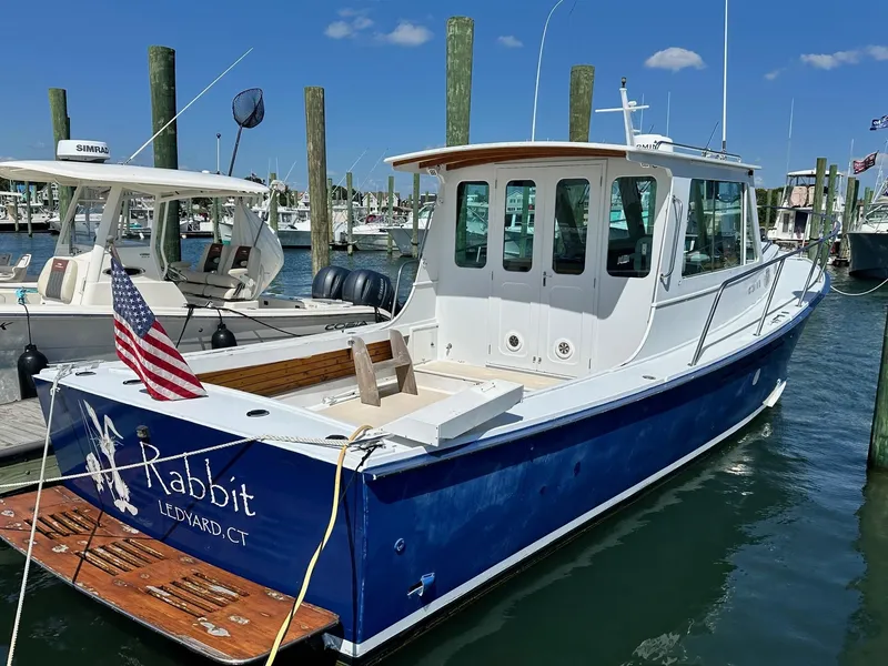 Slide: The Image of Mast & Mallet Rabbit 34 boat, 1998 model, docked with American flag, sunny day. - 2