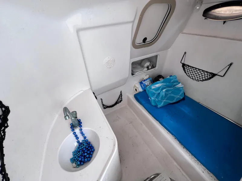 Slide: The Image of Interior cabin of 2006 Hurricane SunDeck 260 OB with sink and blue bedding. - 12