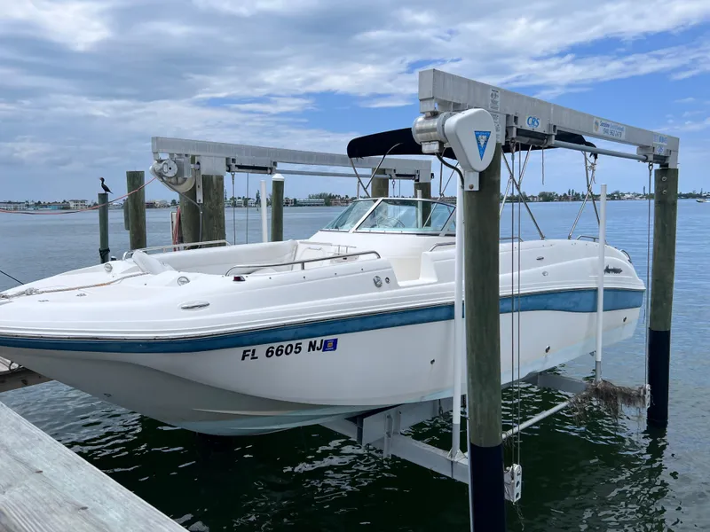 Slide: The Image of 2006 Hurricane SunDeck 260 OB boat on lift, twin Yamaha 150 engines, docked by the water. - 2