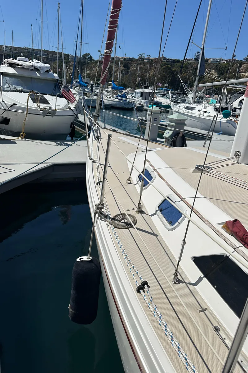 Slide: The Image of 1988 Catalina 30 sailboat docked in a marina, surrounded by other boats. - 26