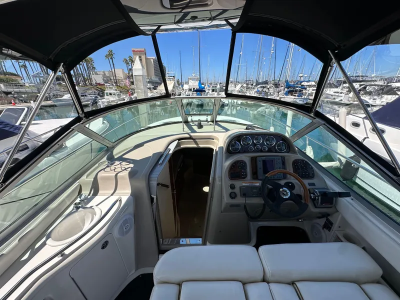 Slide: The Image of 2003 Sea Ray SUNDANCER 300 cockpit with marina view, featuring helm and seating area. - 13
