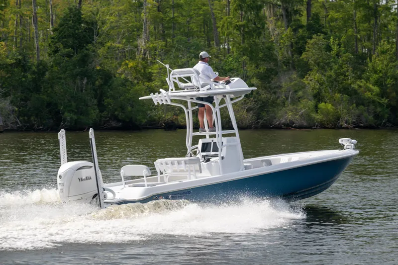 Slide: The Image of 2025 Contender 26 Bay boat cruising on a lake with lush green forest backdrop. - 26