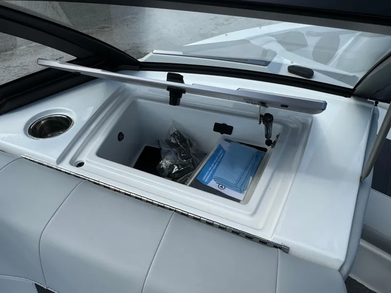 Slide: The Image of 2022 Malibu Wakesetter 20 VTX boat storage compartment with open lid and cup holder. - 29
