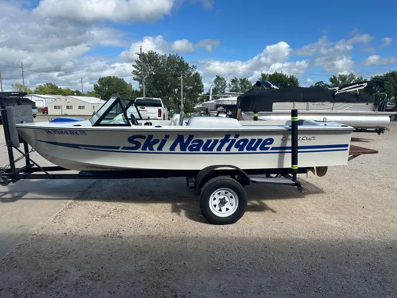Slide: The Image of 1977 Correct Craft Ski Nautique boat on trailer, parked outdoors under a cloudy sky. - 8