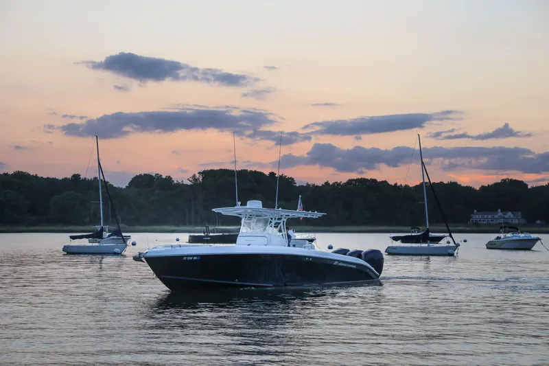 Slide: The Image of 2008 Midnight Express 37 boat on serene water at sunset with sailboats in the background. - 2