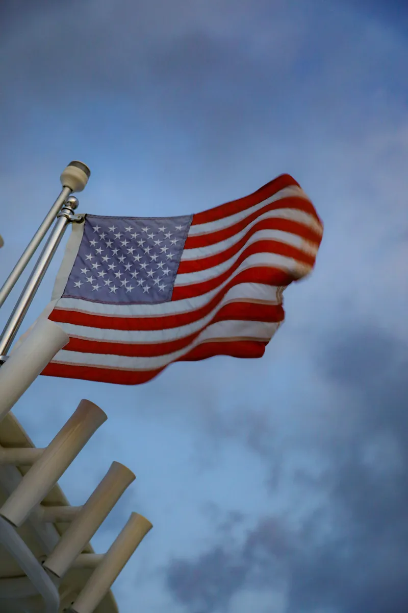 Slide: The Image of American flag waving on a 2008 Midnight Express 37 boat against a cloudy sky. - 30