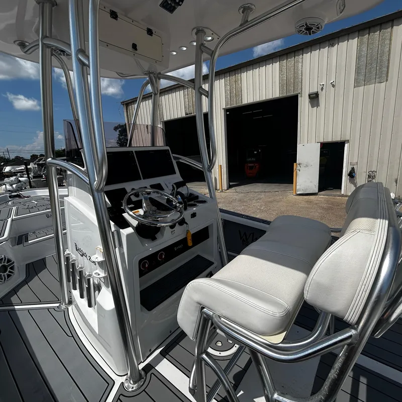 Slide: The Image of 2021 BlackJack 256 Bay boat interior with steering console and cushioned seating. - 16