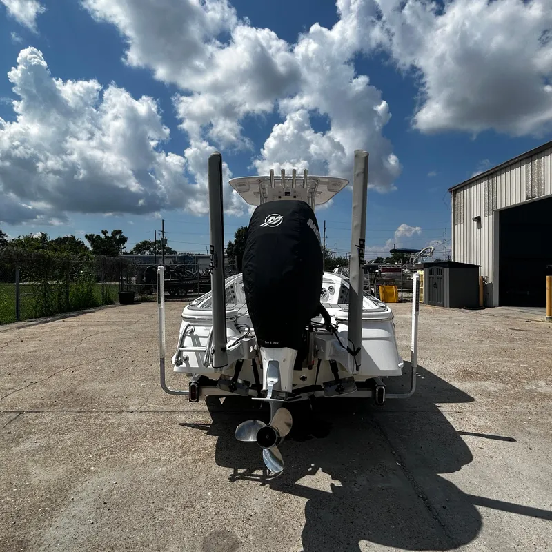 Slide: The Image of 2021 BlackJack 256 Bay boat with covered engine, parked outdoors under cloudy sky. - 5