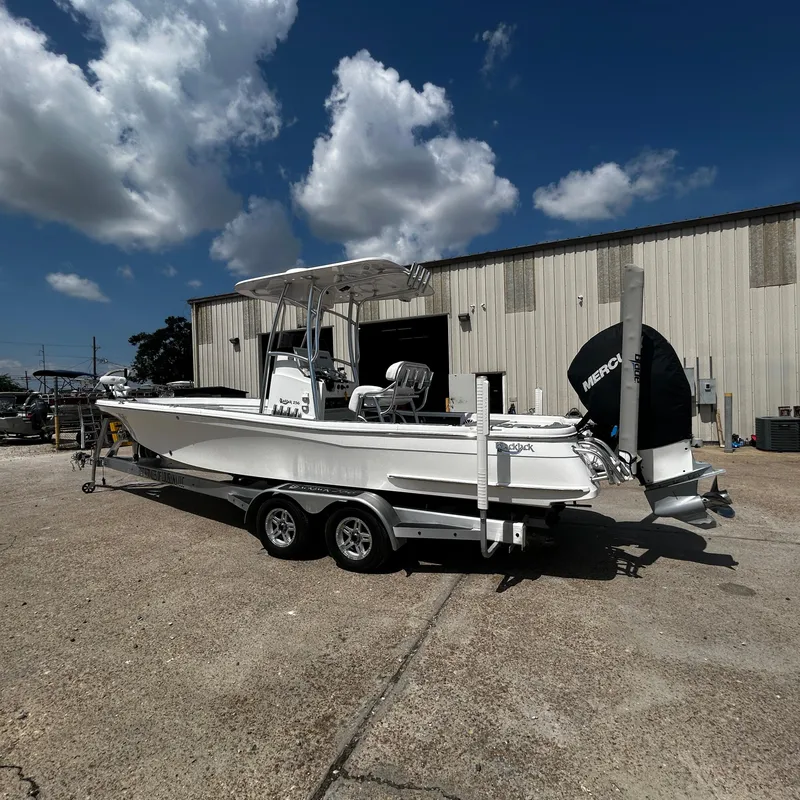 Slide: The Image of 2021 BlackJack 256 Bay boat on trailer, parked outside under a blue sky. - 7
