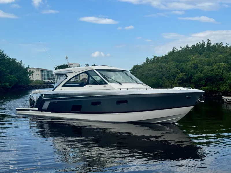 Slide: The Image of 2021 Formula 380 Super Sport Crossover OB boat on calm water, surrounded by greenery. - 1