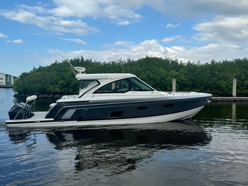 Slide: The Image of 2021 Formula 380 Super Sport Crossover OB on calm water, surrounded by lush greenery. - 2