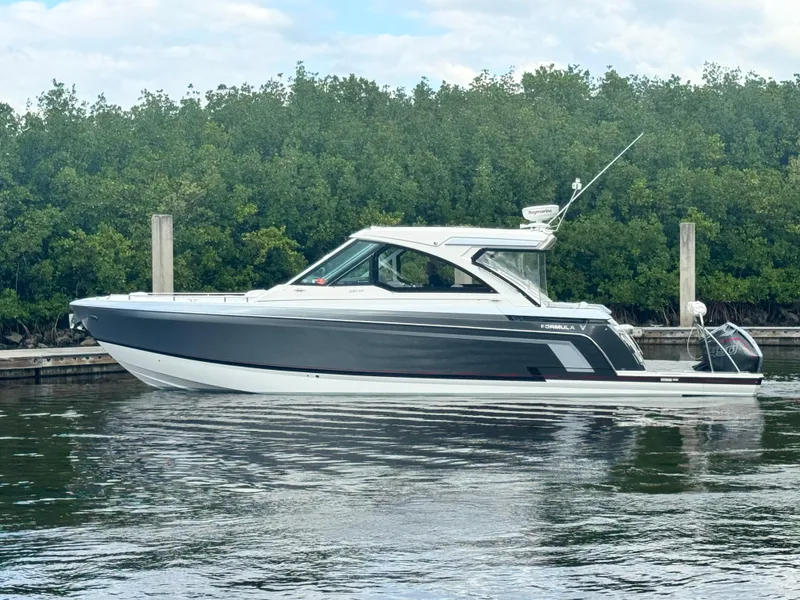 Slide: The Image of 2021 Formula 380 Super Sport Crossover OB boat docked by lush greenery. - 3