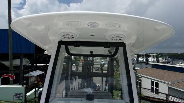 Slide: The Image of 2025 Sportsman Open 212 boat with T-top and speakers, docked under cloudy sky. - 11