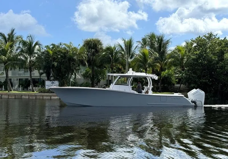 Slide: The Image of 2025 Phenom 37 boat on a calm river, surrounded by palm trees and blue sky. - 0