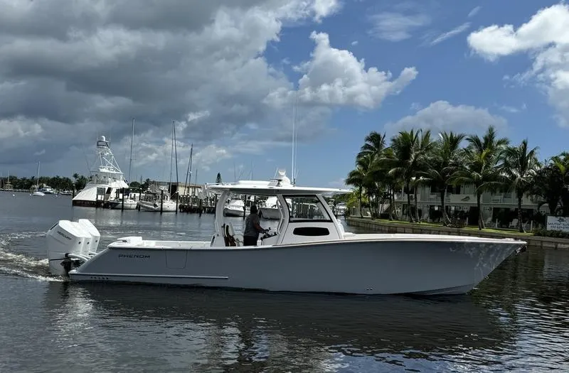 Slide: The Image of Phenom 37 boat cruising on a sunny day in 2025, near a marina. - 2