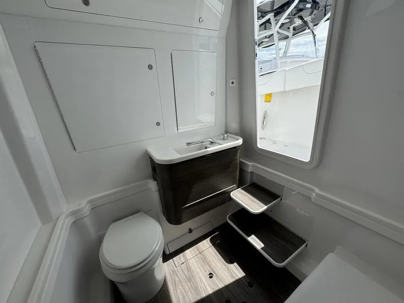 Slide: The Image of Modern bathroom interior on 2025 Phenom 37 boat, featuring toilet, sink, and storage. - 23