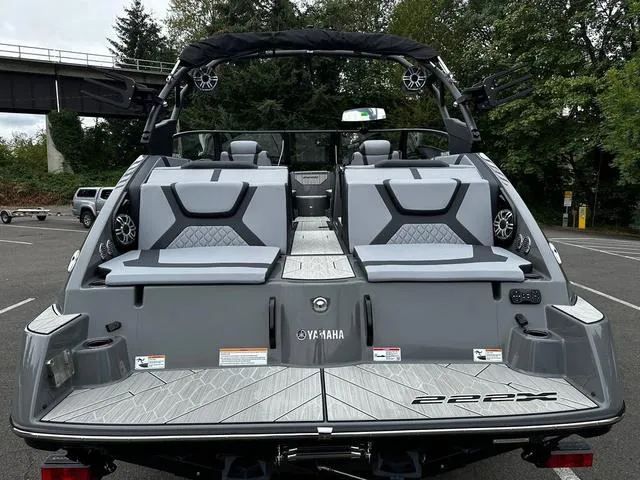 Slide: The Image of 2025 Yamaha Boats 222XD, sleek gray design, spacious seating, parked outdoors. - 10