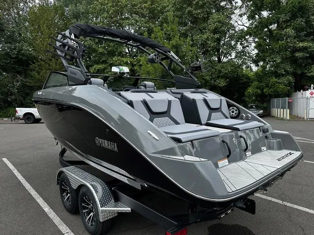 Slide: The Image of 2025 Yamaha Boats 222XD, sleek gray design, parked on trailer in wooded area. - 11