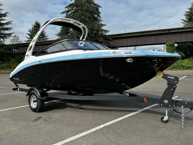 Slide: The Image of 2025 Yamaha Boats 195S on trailer in parking lot, sleek black and blue design. - 5