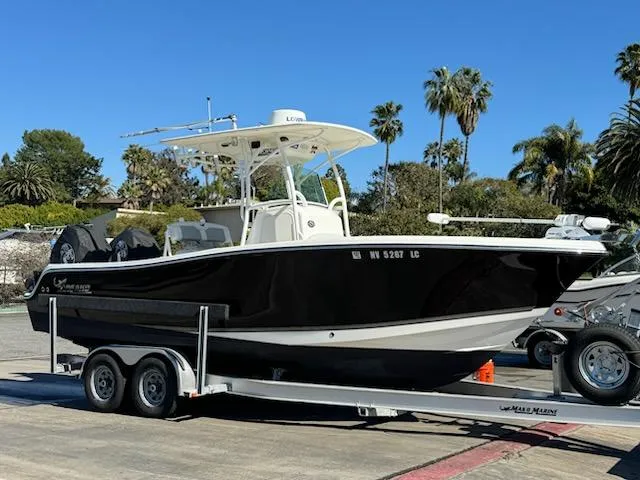 Slide: The Image of 2018 Mako 234 Center Console boat on trailer, parked outdoors with palm trees in background. - 14
