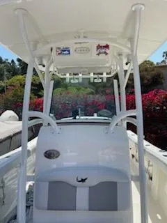 Slide: The Image of 2018 Mako 234 Center Console boat with T-top and seating, surrounded by vibrant foliage. - 3