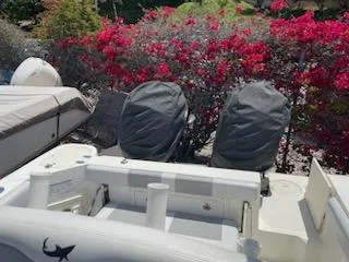 Slide: The Image of 2018 Mako 234 Center Console boat with covered engines, surrounded by vibrant red flowers. - 4