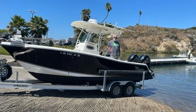 Slide: The Image of 2018 Mako 234 Center Console boat on trailer at boat ramp, sunny day, palm trees in background. - 6